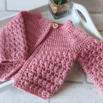 Crochet Baby cardigan in sizes newborn up to 2 years, made with a textured pattern and 1 button fastening. This little jacket is loose enough to go over other clothing