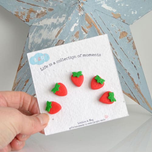A set of five miniature clay strawberry fridge magnets set on seed paper backing