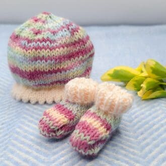 A hand knitted hat and bootee set for a micro preemie baby.