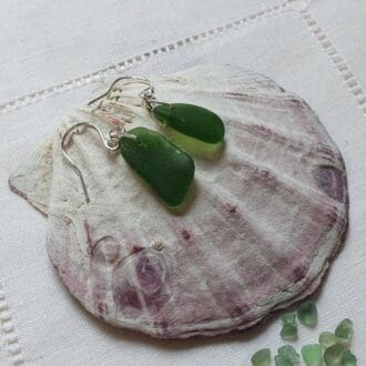 two almost matching pieces of green sea glass with a drilled hole and hanging from silver hook.
