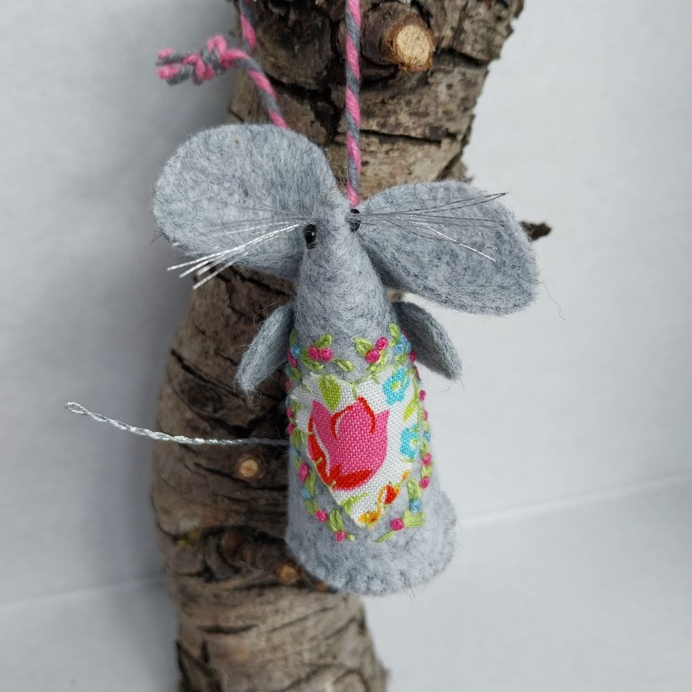 a handmade felt mouse with a fabric heart and contrasting embroidery