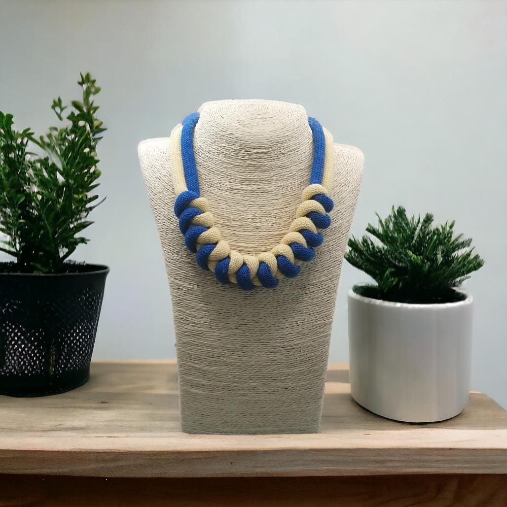 Chunky blue nad yellow knotted rope statement necklace shown on a model bust against a light background.
