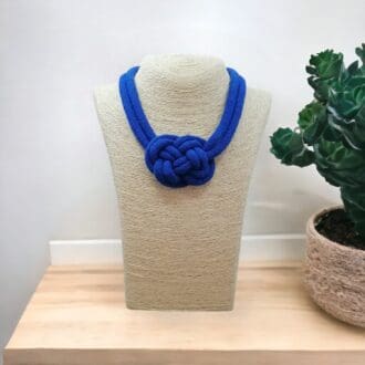 Chunky knotted rope necklace in blue, displayed on a bust model against a light background