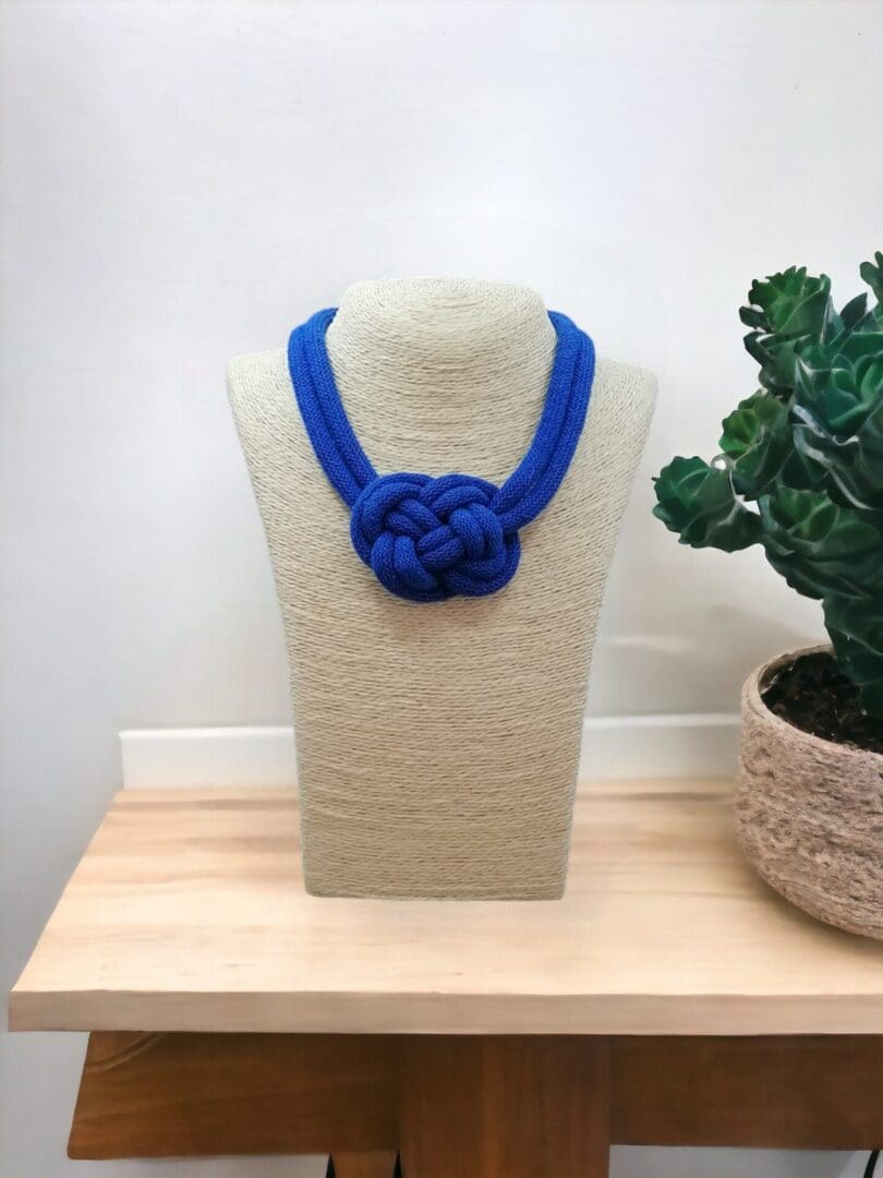 Chunky knotted rope necklace in blue, displayed on a bust model against a light background