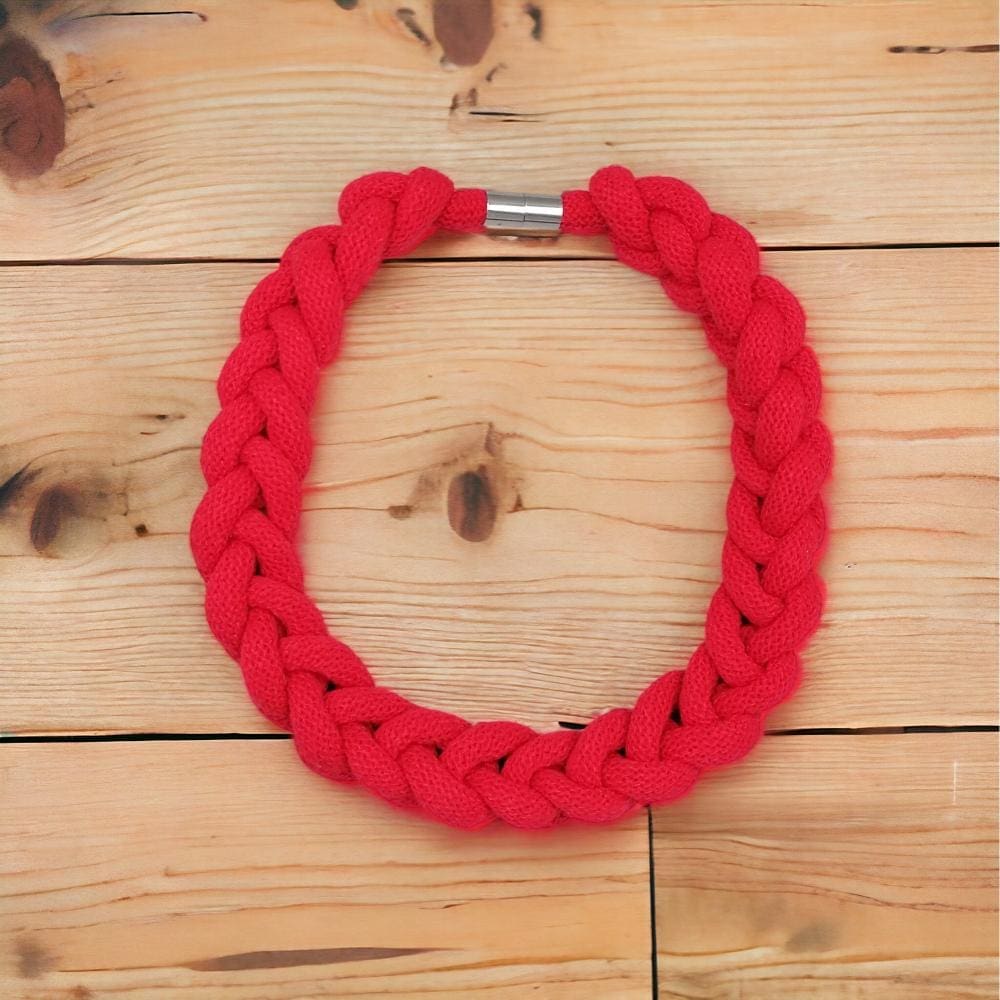 Red chunky statement knotted rope necklace viewed from above on a light wooden background