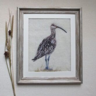 Needle felted wool painting of a curlew on a cream background and in an antique silver wood effect frame.