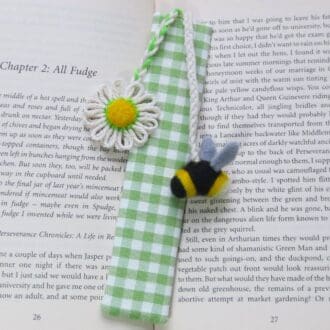 Handmade bookmark in apple green gingham with needle felted bumble bee and a cotton daisy attached by a cord.