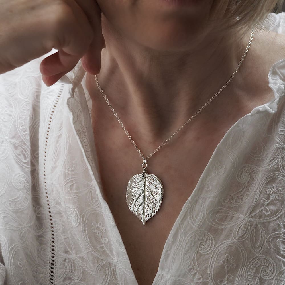 Shiny highly detailed fine silver statement hydrangea leaf pendant necklace shown being worn on a sterling silver rope chain