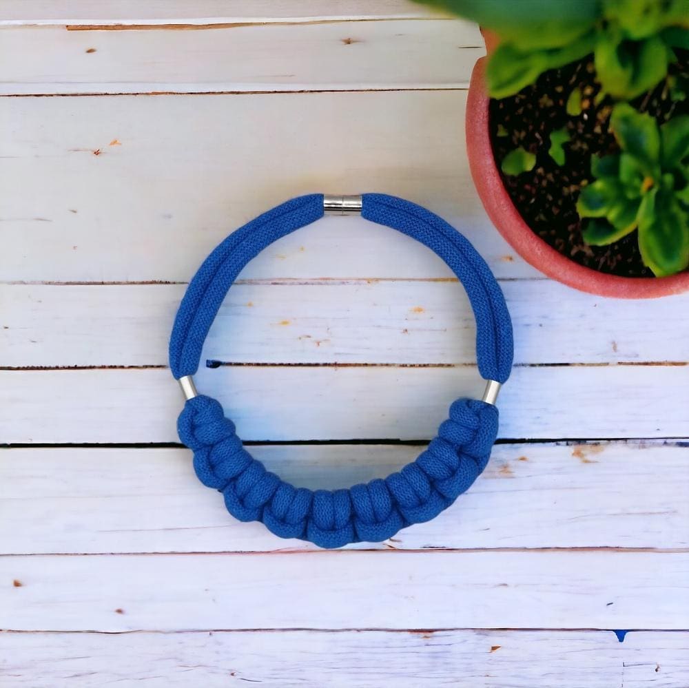 Flatlay over head view of chunky blue statement chunky knotted rope necklace.