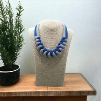 Chunky blue and grey statement necklace made from knotted rope which is displayed ona model bust against a light background