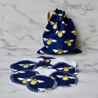 Reusable cotton pads with matching drawstring storage bag. Fabric is Navy with yellow bumble bees. Drawstring on bag is a gold coloured ribbon