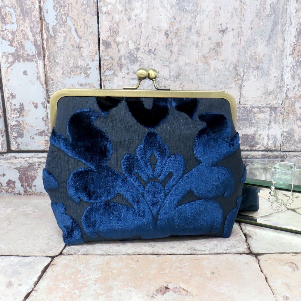 An evening clutch in a navy textured velvet, and with a bronze effect chain handle.