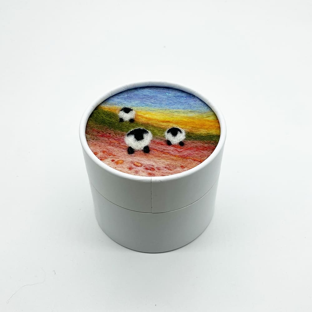 White circular trinket box with a needle felted picture of three sheep on the lid.