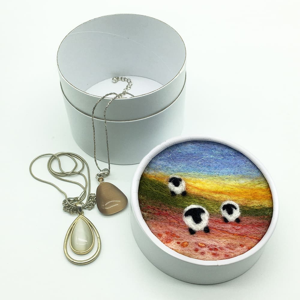 White circular trinket box with a needle felted picture of three sheep on the lid.