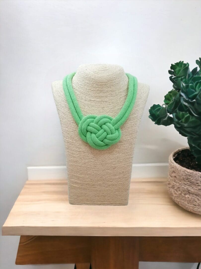 Neon green chunky rope statement necklace with central knot feature, shown on a light bust model against a light background