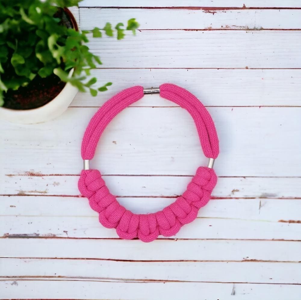 Overhead flatlay view of chunky statement knotted rope pink necklace.