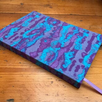 A5 handmade notebook filled with plain white paper covered in blue and purple abstract print fabric