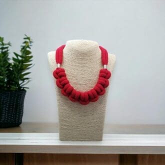 Red chunky knotted rope necklace displayed on bust model against a light background