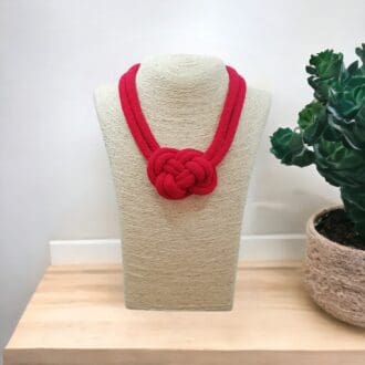 Chunky red rope necklace with central knot feature, displayed on a bust model against a light background