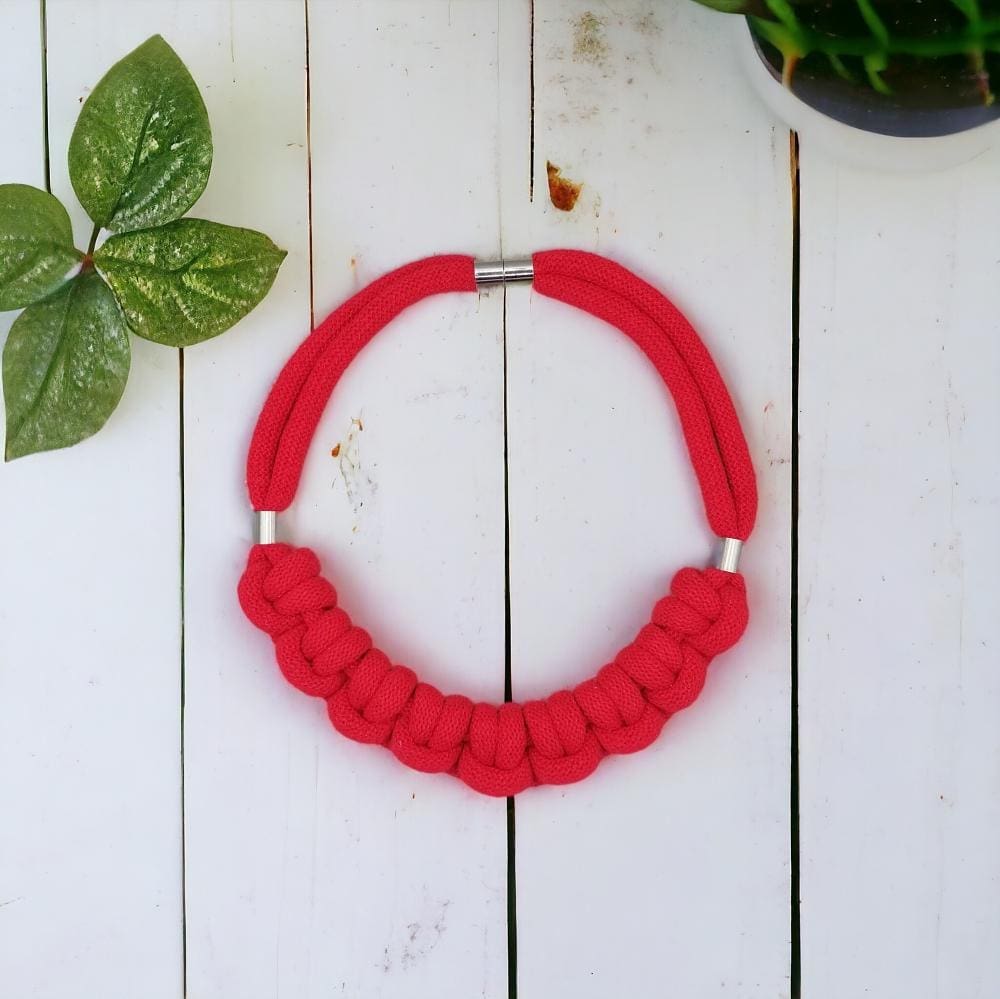 Overhead flatlay view of red chunky knotted rope statement necklace.