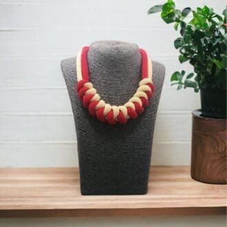 Chunky red and yellow statement rope necklace displayed on a model bust against a light background