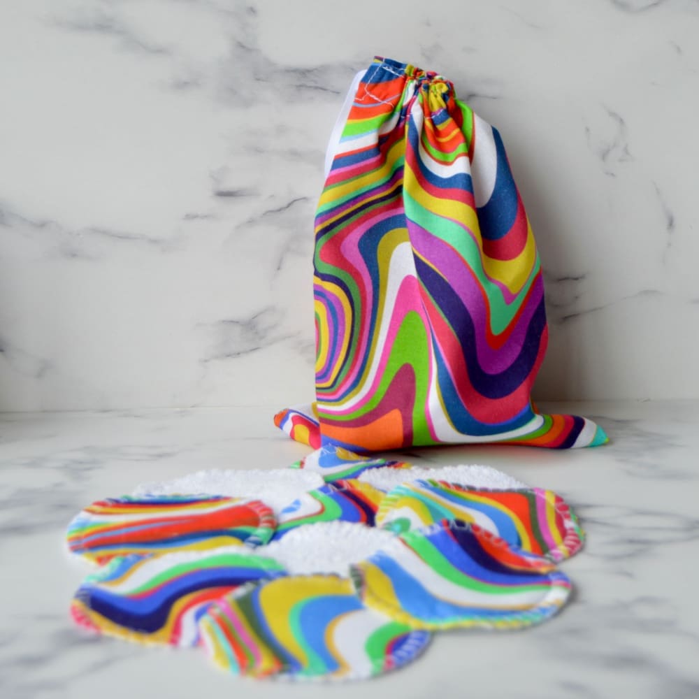 Set of reusable cotton pads with matching drawstring storage bag. Fabric is a wavy retro rainbow design.