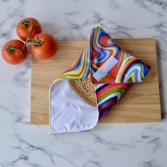 Retro rainbow sandwich wrap placed on a wooden board with tomatoes