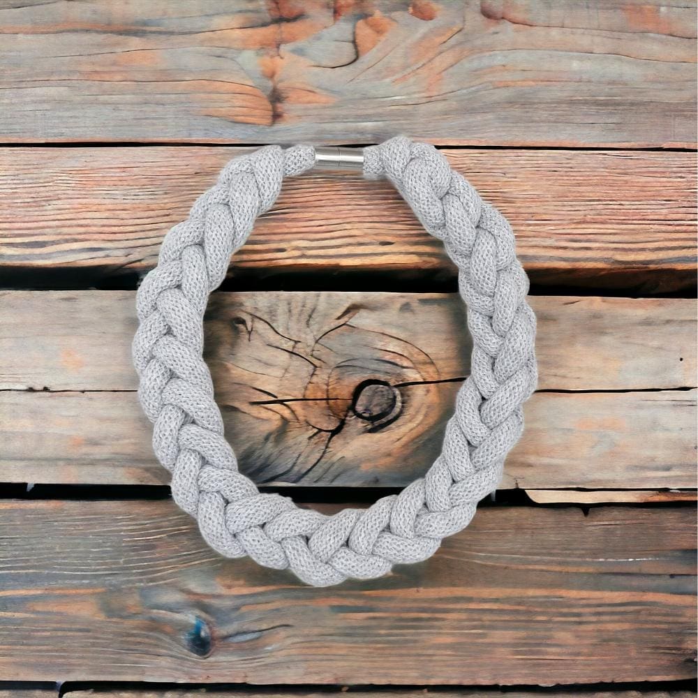 Flatlay over head view of chunky stylish statement knotted necklace displayed against a light wooden background