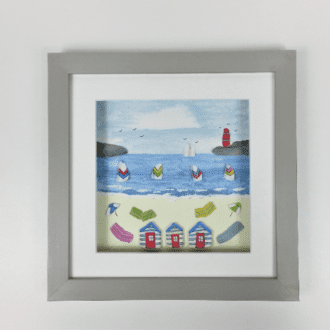 beach scene featuring beach huts, colourful wind breaks and windsurfers made from beachcombed finds set inside a 24cm glazed frame