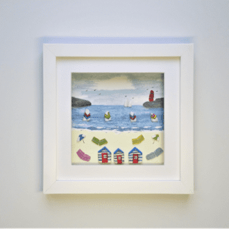 framed picture of a seaside scene with beach huts, windbreaks and lighthouse all made from Cornish beachcombed finds