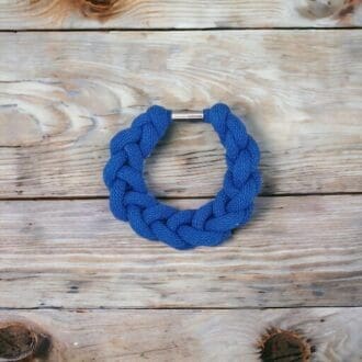 Blue chunky knotted rope bracelet viewed from above against a wodden countertop background.