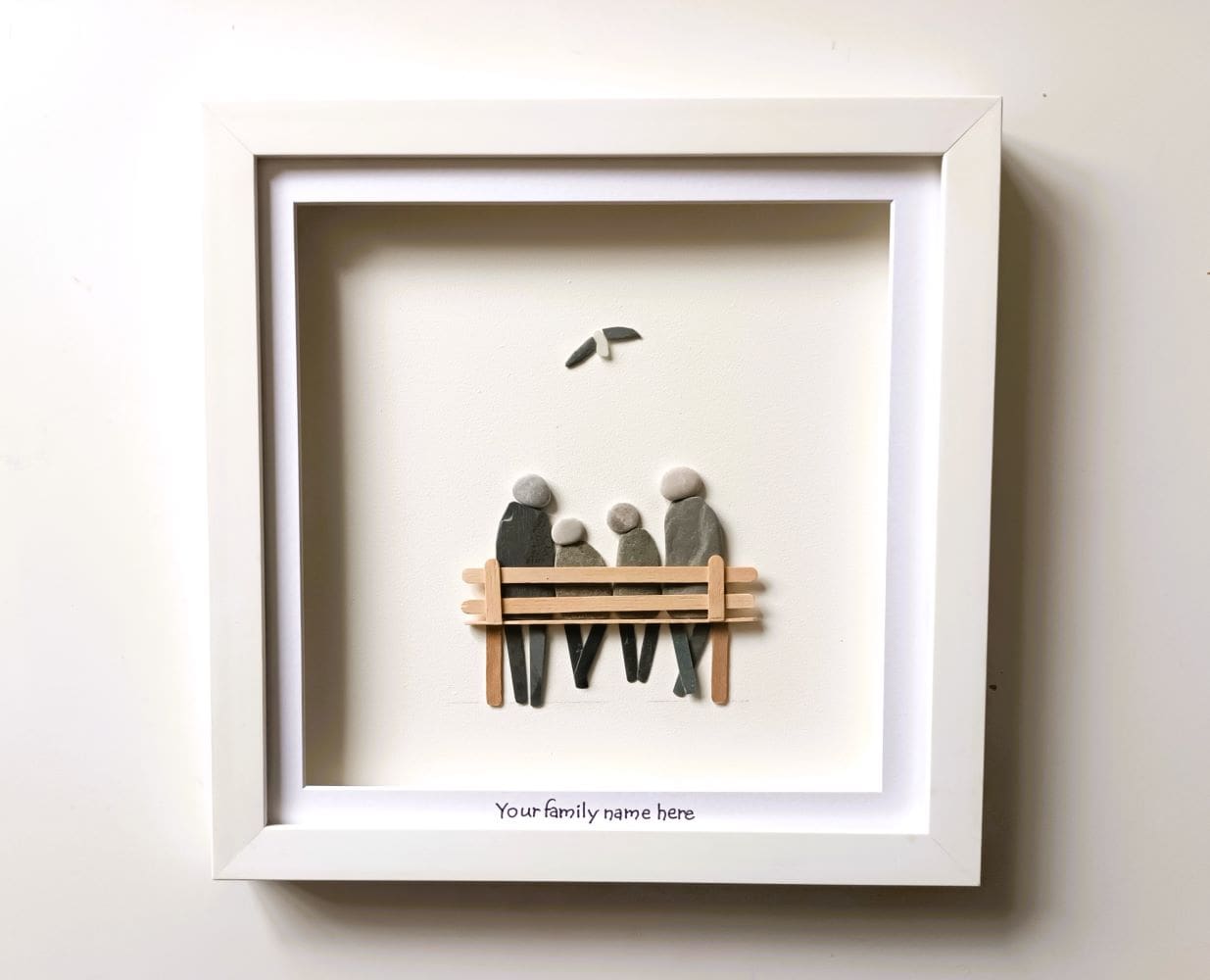 Framed portrait of family of four depicted in stone sitting on a wooden bench