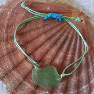 green seaglass bracelet sits on shell