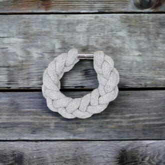 Chunky grey stylish statement bracelet viewed from above against a wooden background.