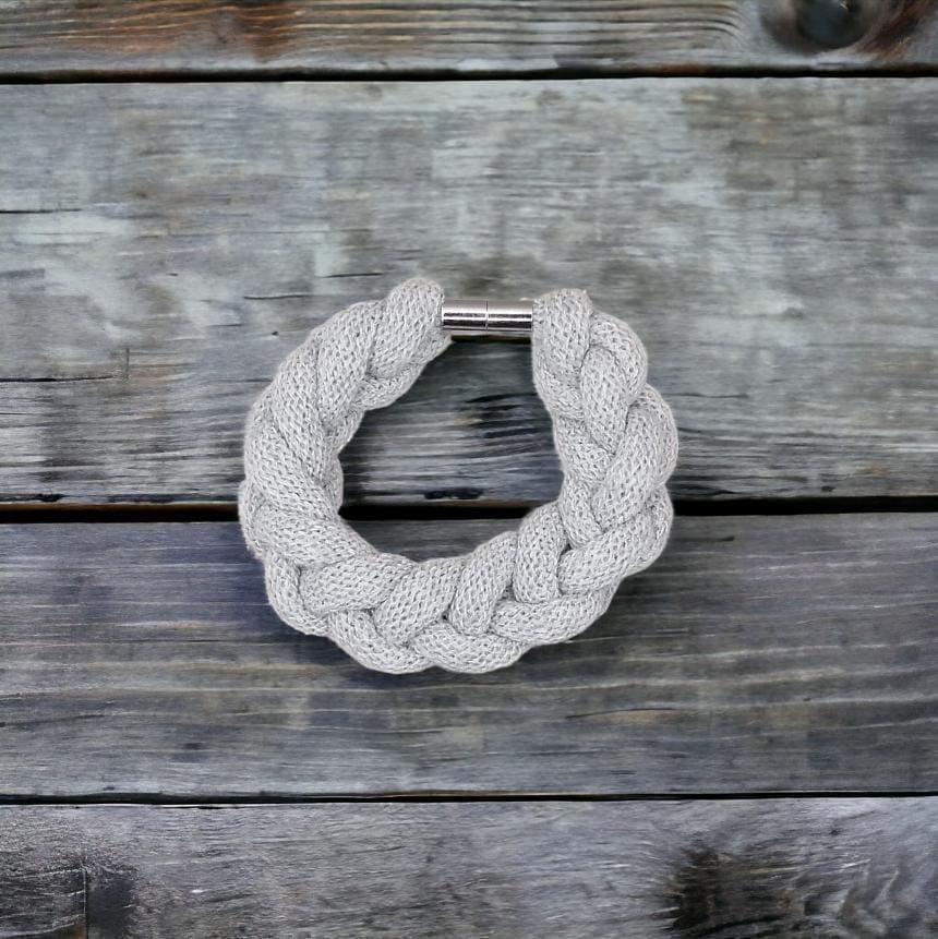 Chunky grey stylish statement bracelet viewed from above against a wooden background.