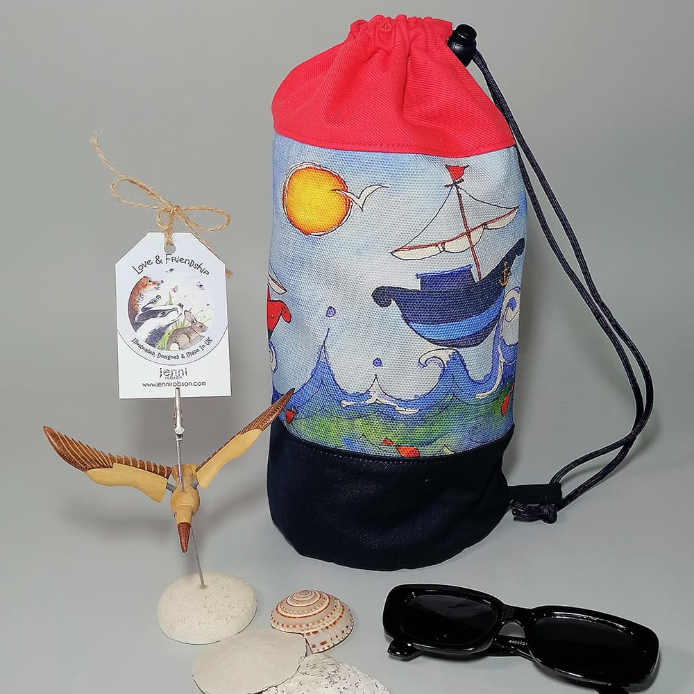 Kids red top duffle bag with sail boat print and navy blue base ready for the beach along with kids sunglasses and shells
