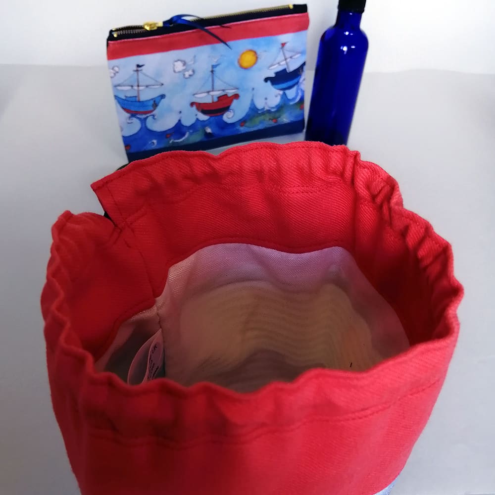 Kids red top duffle bag with sail boat print and navy blue base - detail showing the drawstring closure which has a chunky toggle fastening