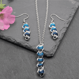 A matching pendant and earrings set made up of a section of barrel weave chainmaille weave. made with bright aluminium and different shades of blue anodised aluminium rings