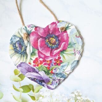 Slate heart painted white and decoupaged with a bold pink and purple floral design and finished with a twine hanger.