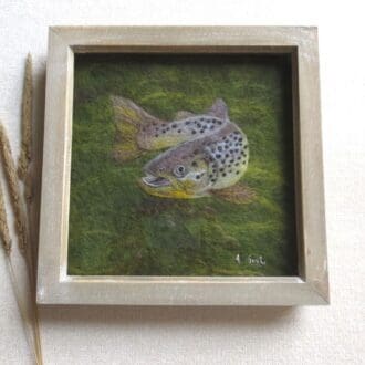 A handmade needle felted picture of a brown trout on a dark green wet felted background in a natural wood box frame.