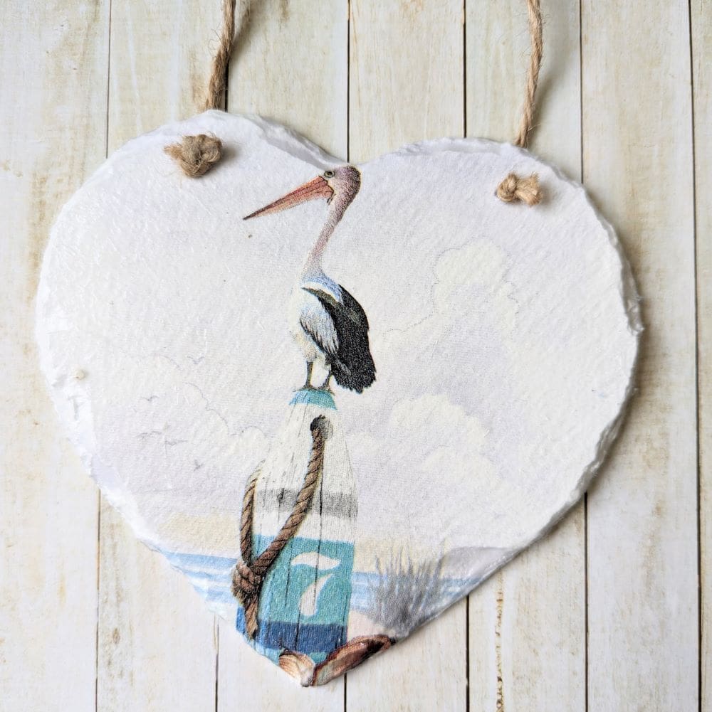 Slate hanging heart painted white and decoupaged with a simple coastal pelican design. Finished with a twine hanger