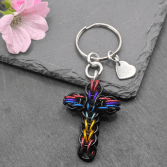 A keyring made with black and rainbow coloured rings woven in the full persian chainmaille weave into a cross