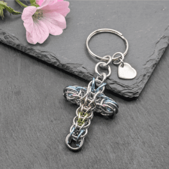 A keyring made with silver and pastel coloured rings woven in the full persian chainmaille weave into a cross