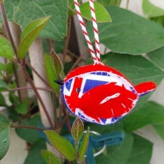 A hand sewn red and blue felt bird with union flag fabric sides