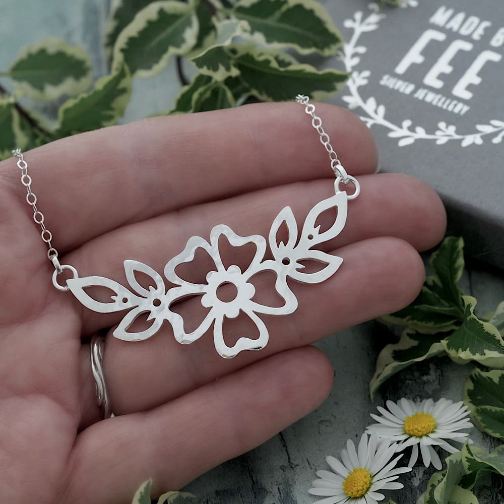 55mm x 25mm Hammered Cutwork Sterling silver flower and leaf motif pendant on a delicate flat trace chain shown on hand