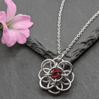 Helm flower chainmaille pendant made with silver coloured and red aluminium rings on a stainless steel chain