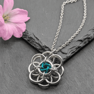 Helm flower chainmaille pendant made from bright aluminium and sea green anodized aluminium rings on a stainless steel chain