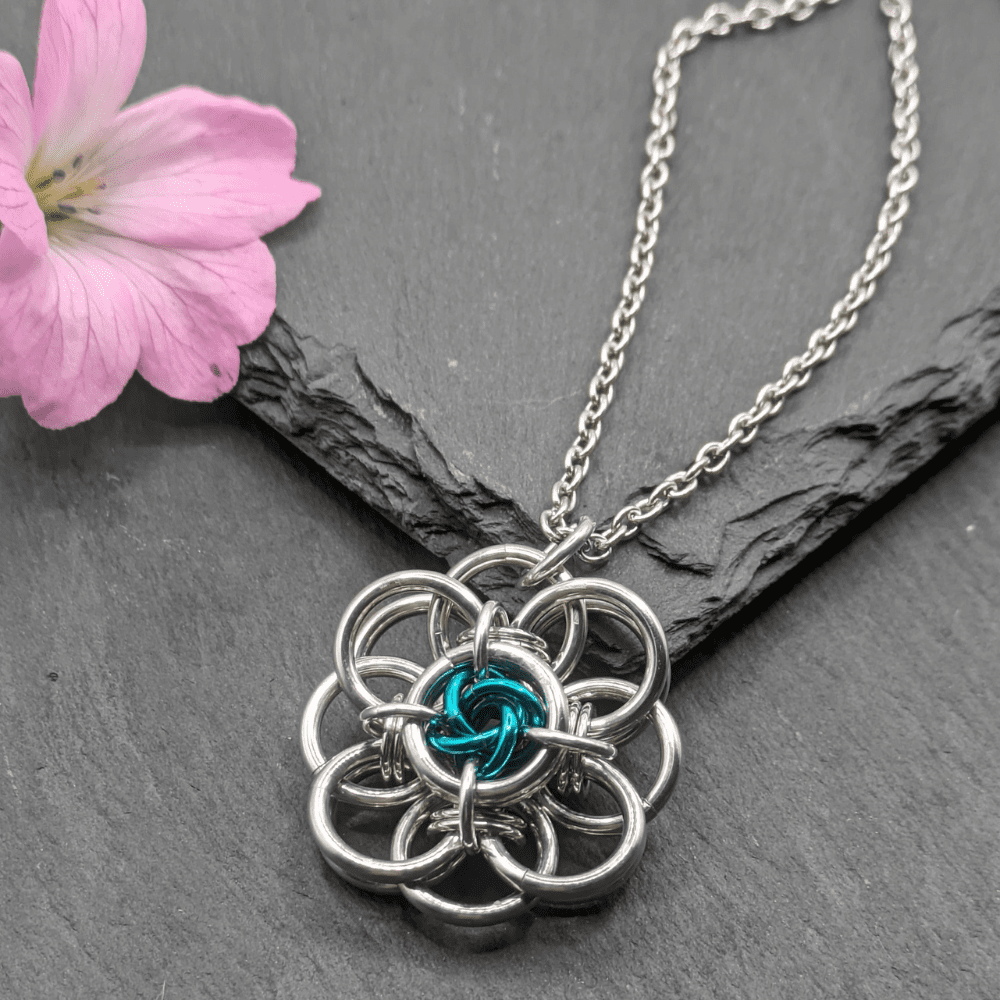 Helm flower chainmaille pendant made from bright aluminium and sea green anodized aluminium rings on a stainless steel chain