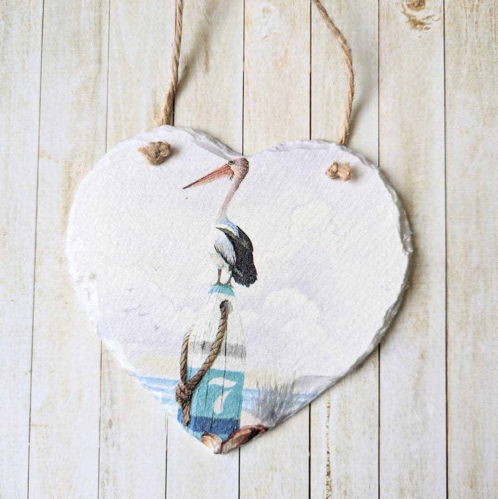 Slate hanging heart painted white and decoupaged with a simple coastal pelican design. Finished with a twine hanger