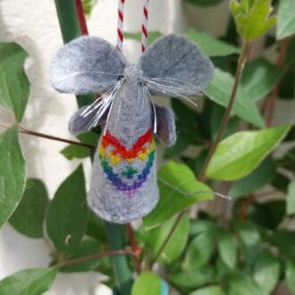 A hand embroidered felt mouse with a rainbow coloured cross stitch heart design